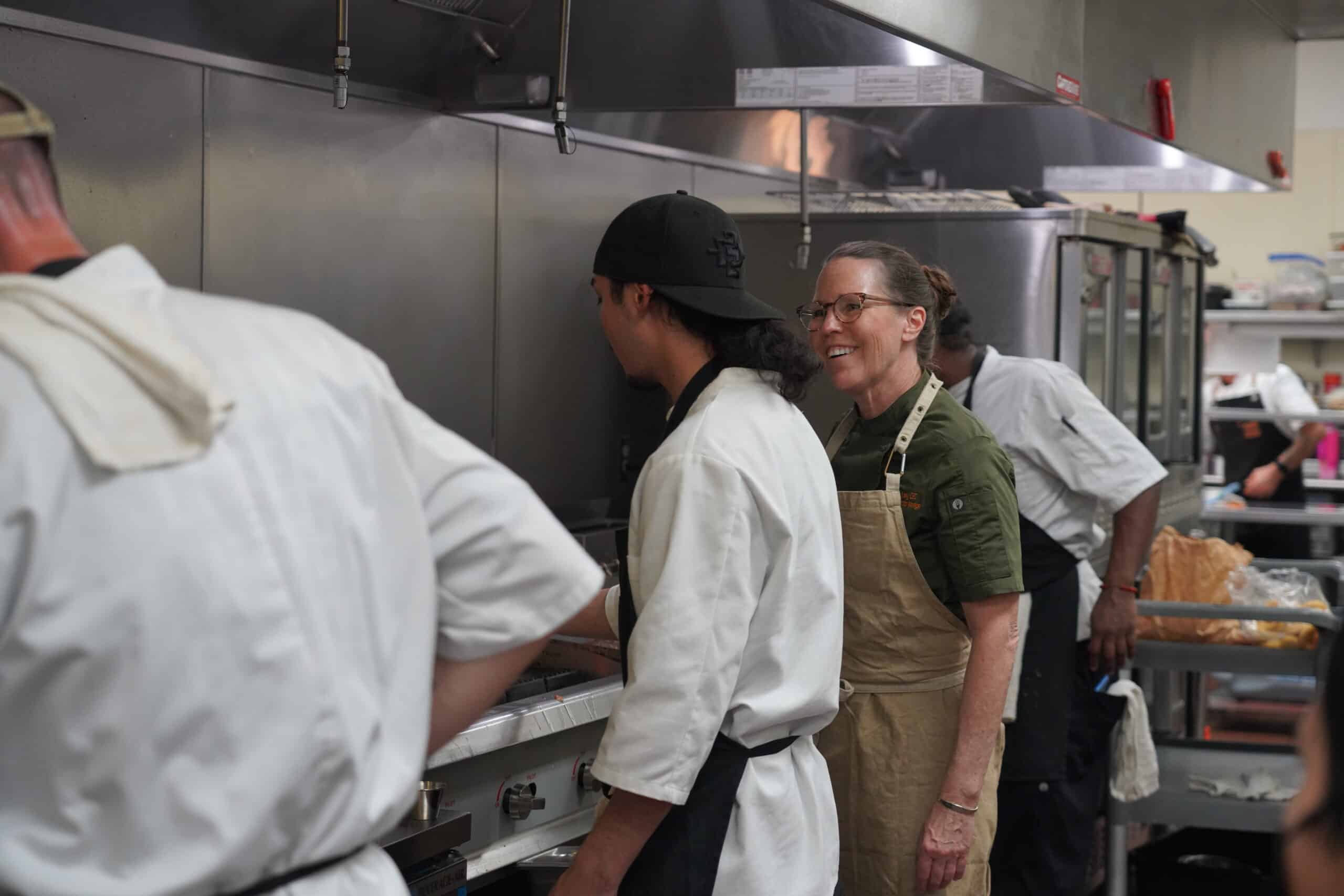 Youth participants and an instructor working together in the kitchen during culinary training